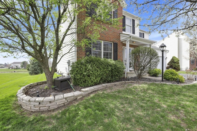view of side of property featuring brick siding and a yard