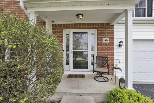 entrance to property with brick siding, an attached garage, and a porch