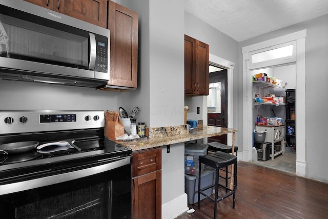 940 3rd St, Logan, OH 43138 - kitchen featuring stainless steel microwave, electric stove, dark wood-style flooring, a kitchen bar, and light stone counters