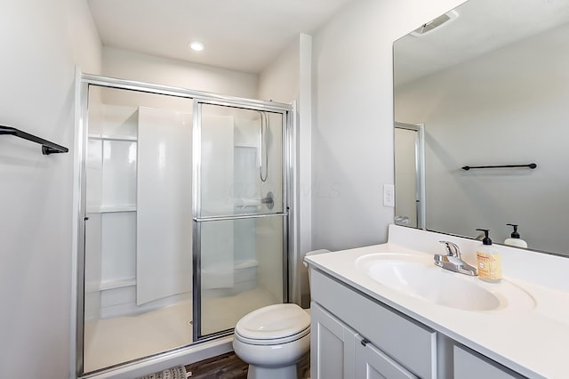 full bathroom featuring toilet, vanity, wood finished floors, and a stall shower