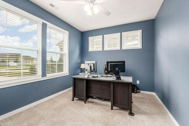 carpeted office space featuring baseboards, a ceiling fan, and visible vents