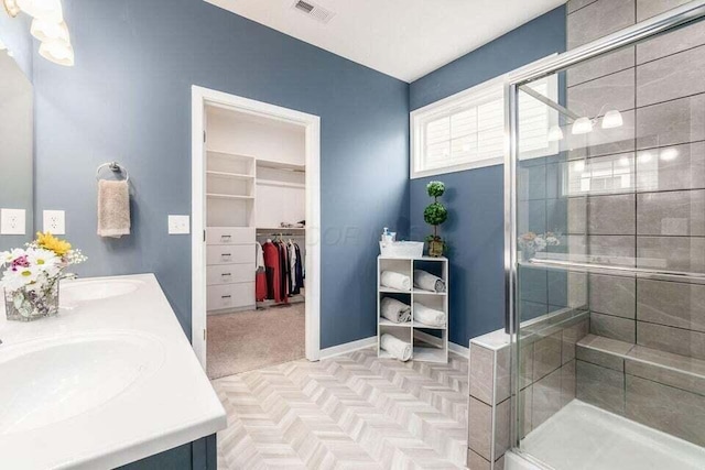 full bathroom featuring visible vents, a sink, a shower stall, and a walk in closet