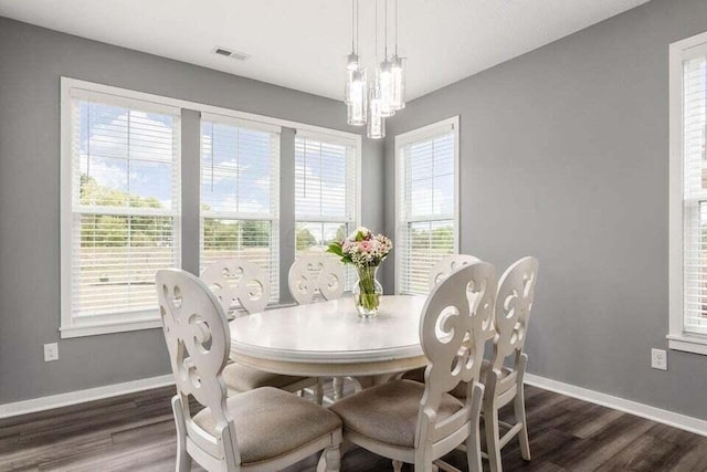 dining area featuring dark wood-type flooring, a chandelier, visible vents, and baseboards