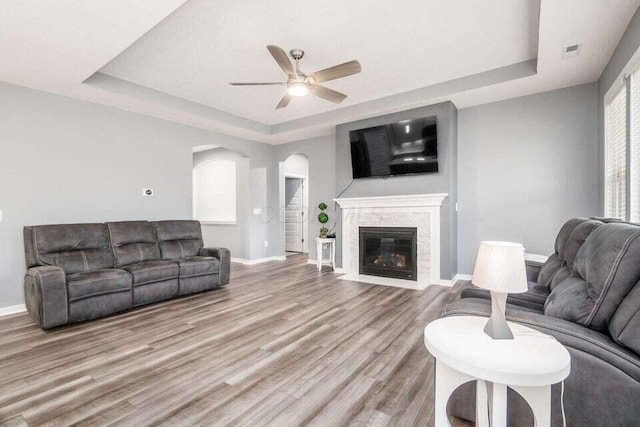 living room with ceiling fan, baseboards, and a raised ceiling