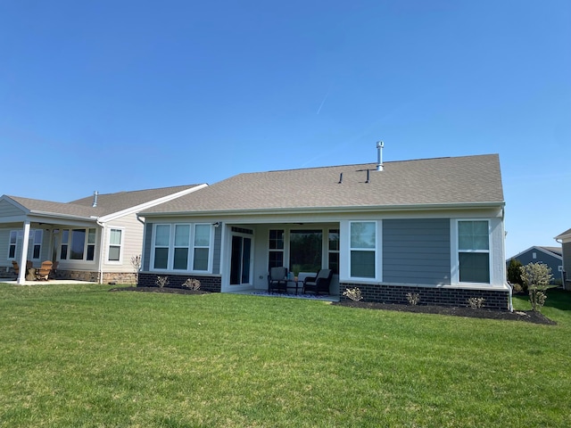 rear view of house with brick siding, a yard, and a patio