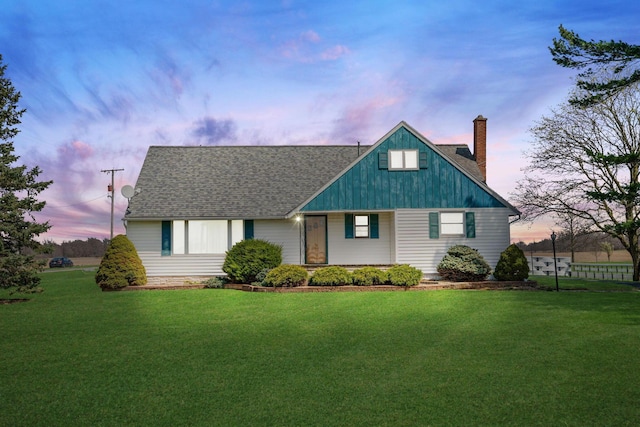 view of front of home featuring a chimney, a shingled roof, and a lawn