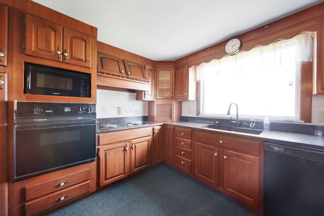 kitchen featuring brown cabinetry, black appliances, a sink, and plenty of natural light