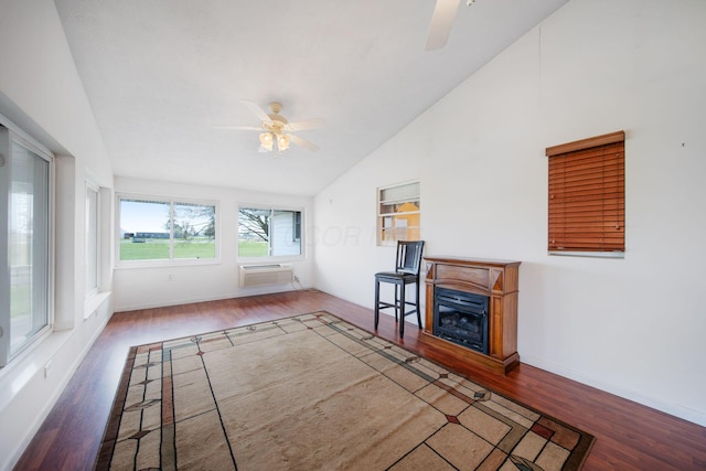 unfurnished living room with high vaulted ceiling, wood finished floors, a wall mounted AC, ceiling fan, and baseboards