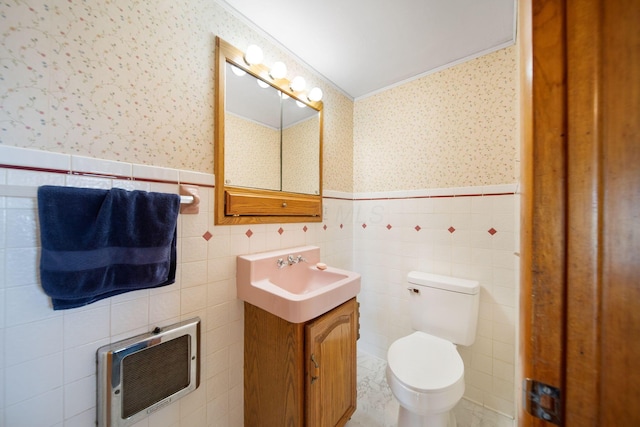 bathroom with wallpapered walls, toilet, heating unit, and wainscoting