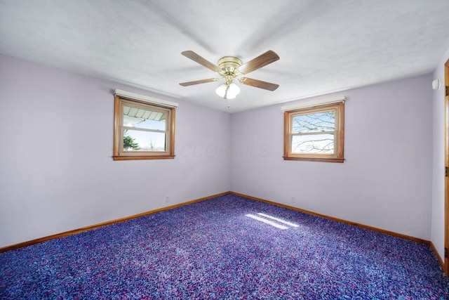 carpeted spare room featuring a wealth of natural light, baseboards, and ceiling fan