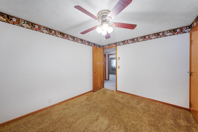 carpeted empty room with baseboards and a ceiling fan
