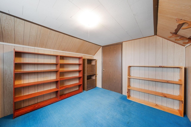 bonus room with vaulted ceiling, wood walls, and carpet floors