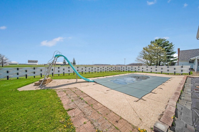 view of swimming pool featuring a lawn and fence