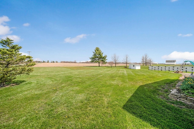 view of yard featuring a rural view, an outbuilding, and a storage unit