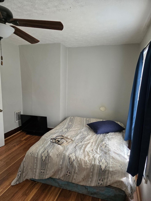bedroom with wood finished floors, a ceiling fan, and a textured ceiling