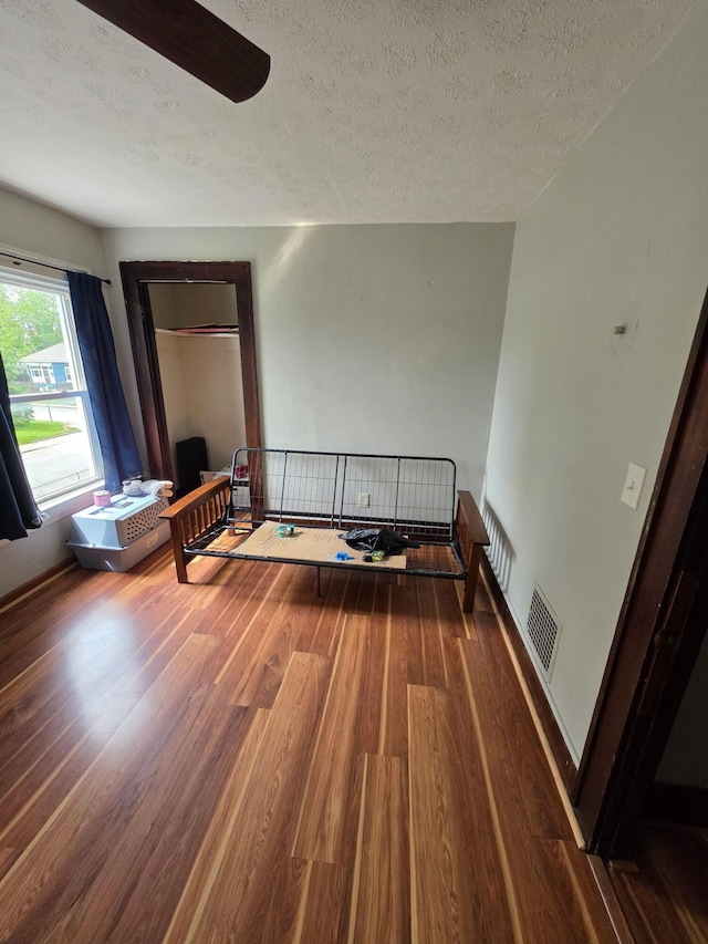 bedroom with a textured ceiling, wood finished floors, and radiator