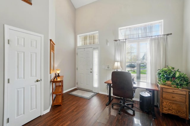 office space featuring baseboards, a high ceiling, and wood finished floors