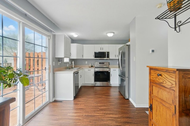 kitchen with light countertops, dark wood finished floors, stainless steel appliances, baseboards, and white cabinetry