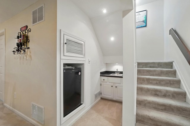 staircase featuring carpet, vaulted ceiling, and visible vents
