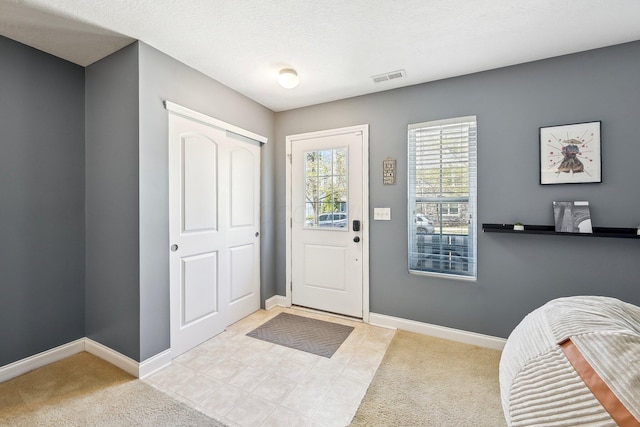 foyer featuring visible vents, baseboards, and carpet floors