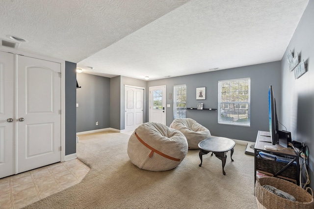 living area featuring baseboards, carpet flooring, a textured ceiling, and visible vents