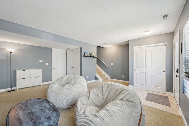 living area with baseboards, stairs, a textured ceiling, and visible vents