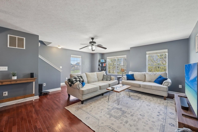 living room with visible vents, hardwood / wood-style floors, baseboards, ceiling fan, and a textured ceiling