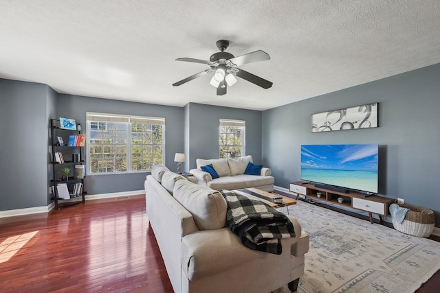 living area featuring a textured ceiling, baseboards, ceiling fan, and wood finished floors