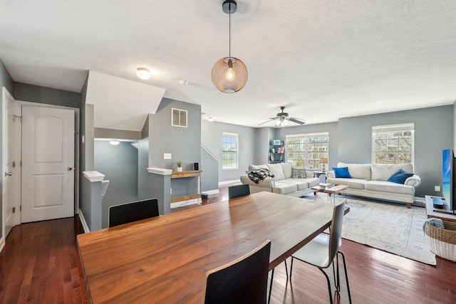 dining area featuring ceiling fan, a textured ceiling, baseboards, visible vents, and dark wood-style floors