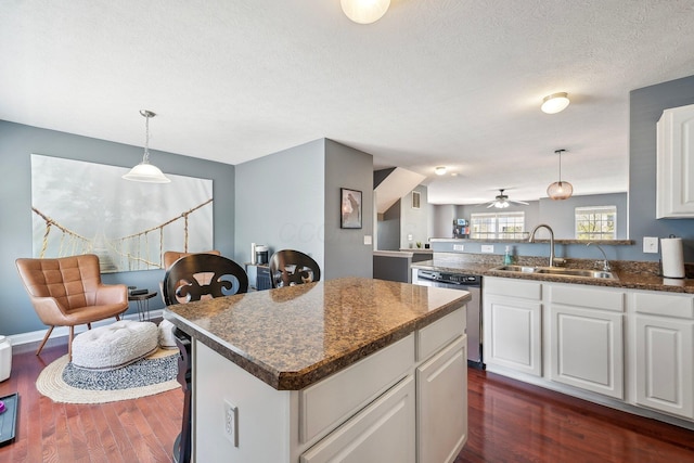 kitchen with a sink, white cabinets, stainless steel dishwasher, and dark wood-type flooring