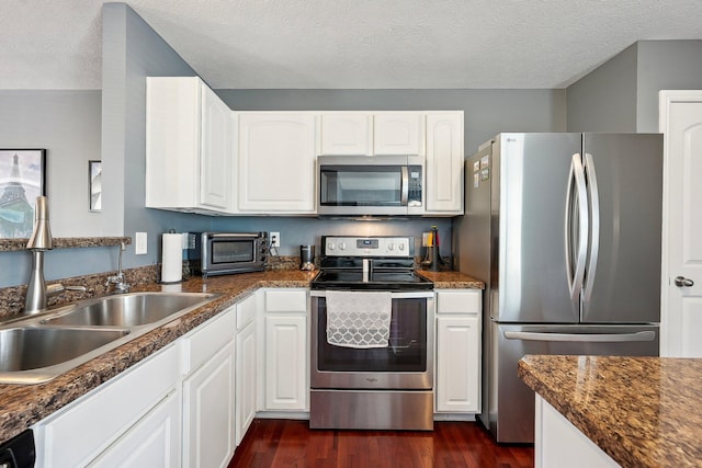 kitchen featuring a sink, appliances with stainless steel finishes, a toaster, and dark countertops