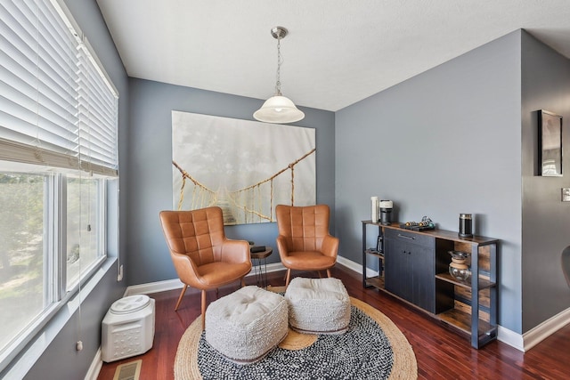 living area with baseboards, a wealth of natural light, wood finished floors, and visible vents
