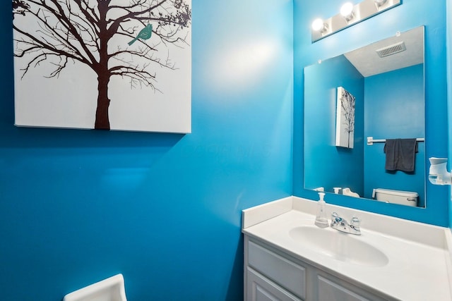 bathroom featuring vanity, toilet, and visible vents