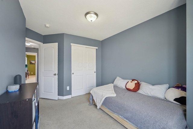 carpeted bedroom with baseboards and a closet