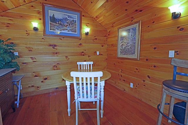 dining room with hardwood / wood-style floors, wooden ceiling, wooden walls, and vaulted ceiling