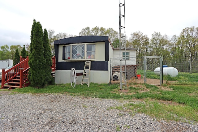 rear view of property featuring fence and a gate