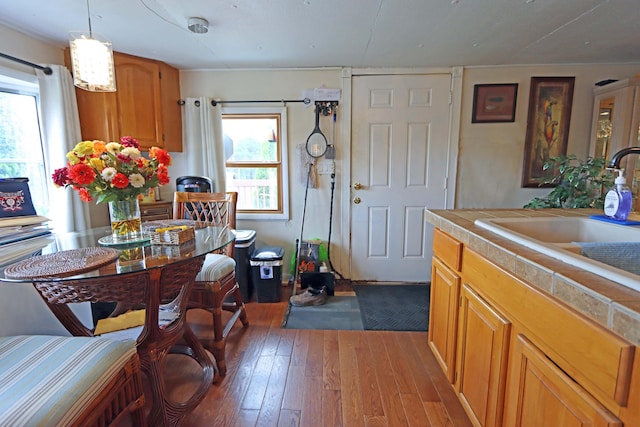 kitchen with wood-type flooring, a sink, brown cabinets, and tile countertops