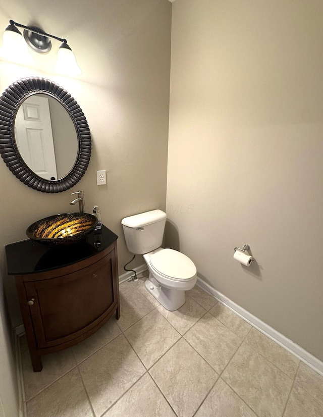 half bathroom featuring toilet, baseboards, tile patterned floors, and vanity