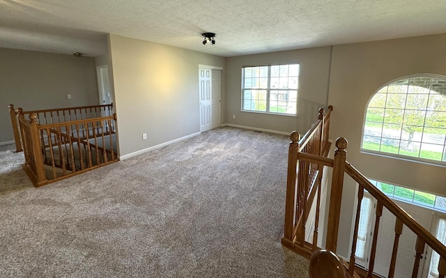 carpeted spare room with baseboards and a textured ceiling