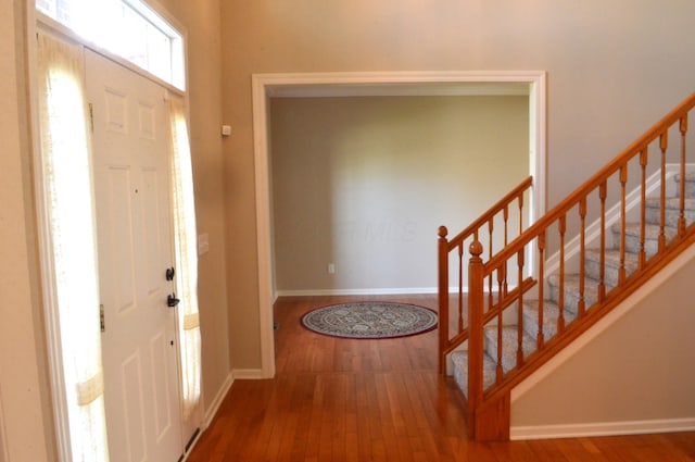 entryway featuring baseboards, stairs, and hardwood / wood-style floors