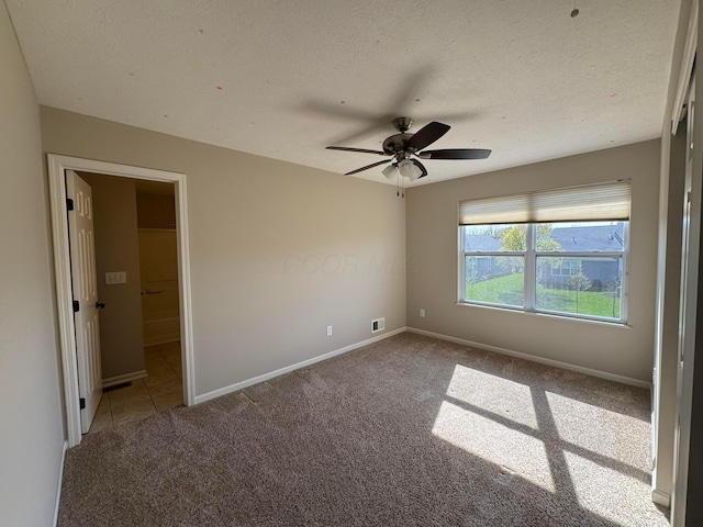 unfurnished bedroom featuring a textured ceiling, visible vents, baseboards, connected bathroom, and carpet