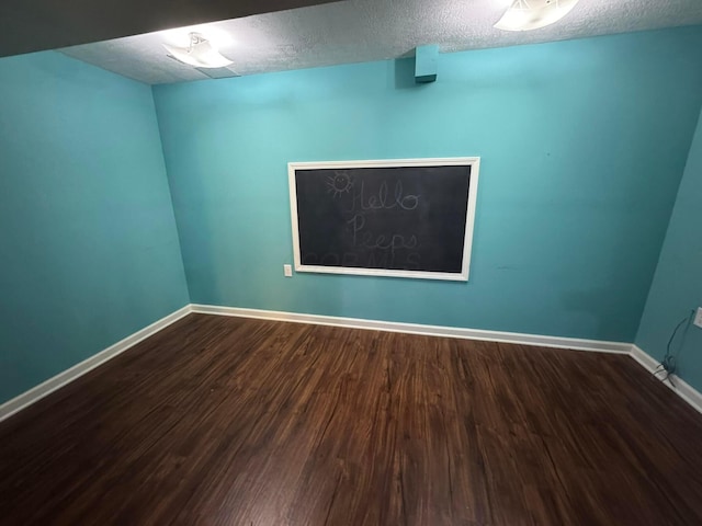 unfurnished room featuring a textured ceiling, baseboards, and wood finished floors