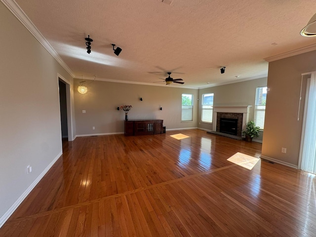 unfurnished living room featuring crown molding, a textured ceiling, baseboards, and hardwood / wood-style flooring