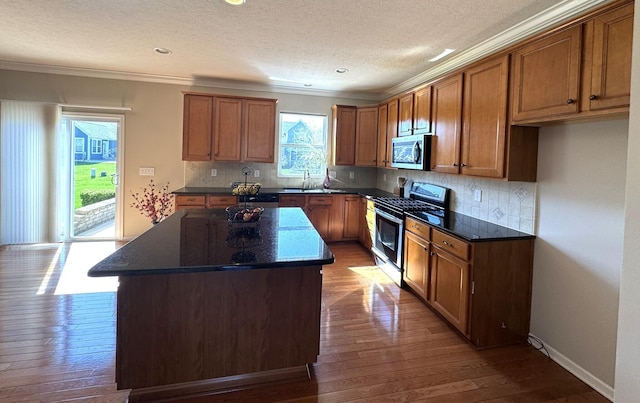 kitchen featuring crown molding, brown cabinets, a sink, stainless steel appliances, and dark wood-type flooring