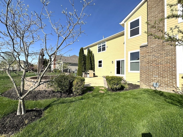 back of property featuring a lawn, a patio, and brick siding