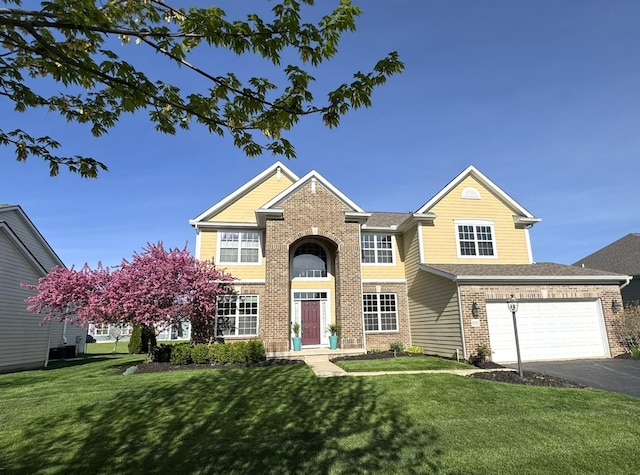 traditional-style home with brick siding, a garage, a front lawn, and aphalt driveway