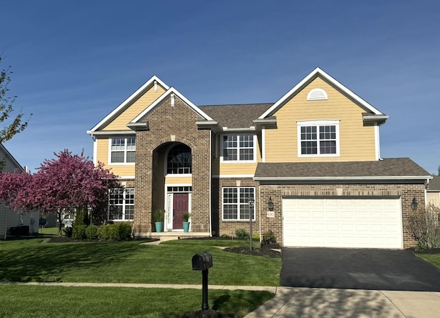 traditional-style home with driveway, a front lawn, and brick siding