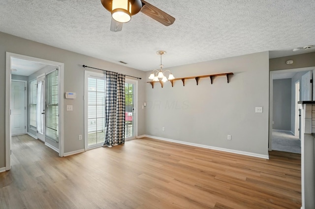 unfurnished dining area featuring visible vents, light wood finished floors, baseboards, and ceiling fan with notable chandelier