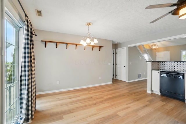 unfurnished living room with light wood-style flooring, a textured ceiling, baseboards, and visible vents