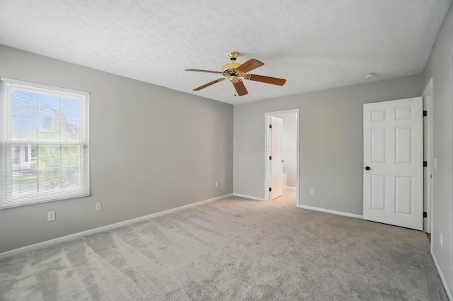 unfurnished bedroom featuring a textured ceiling, connected bathroom, ceiling fan, carpet floors, and baseboards